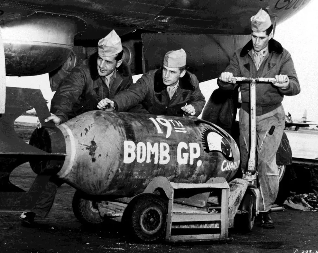 koren war a A 2,000-pound bomb is being carefully loaded into the bomb bay of a b-29 by three crewmen